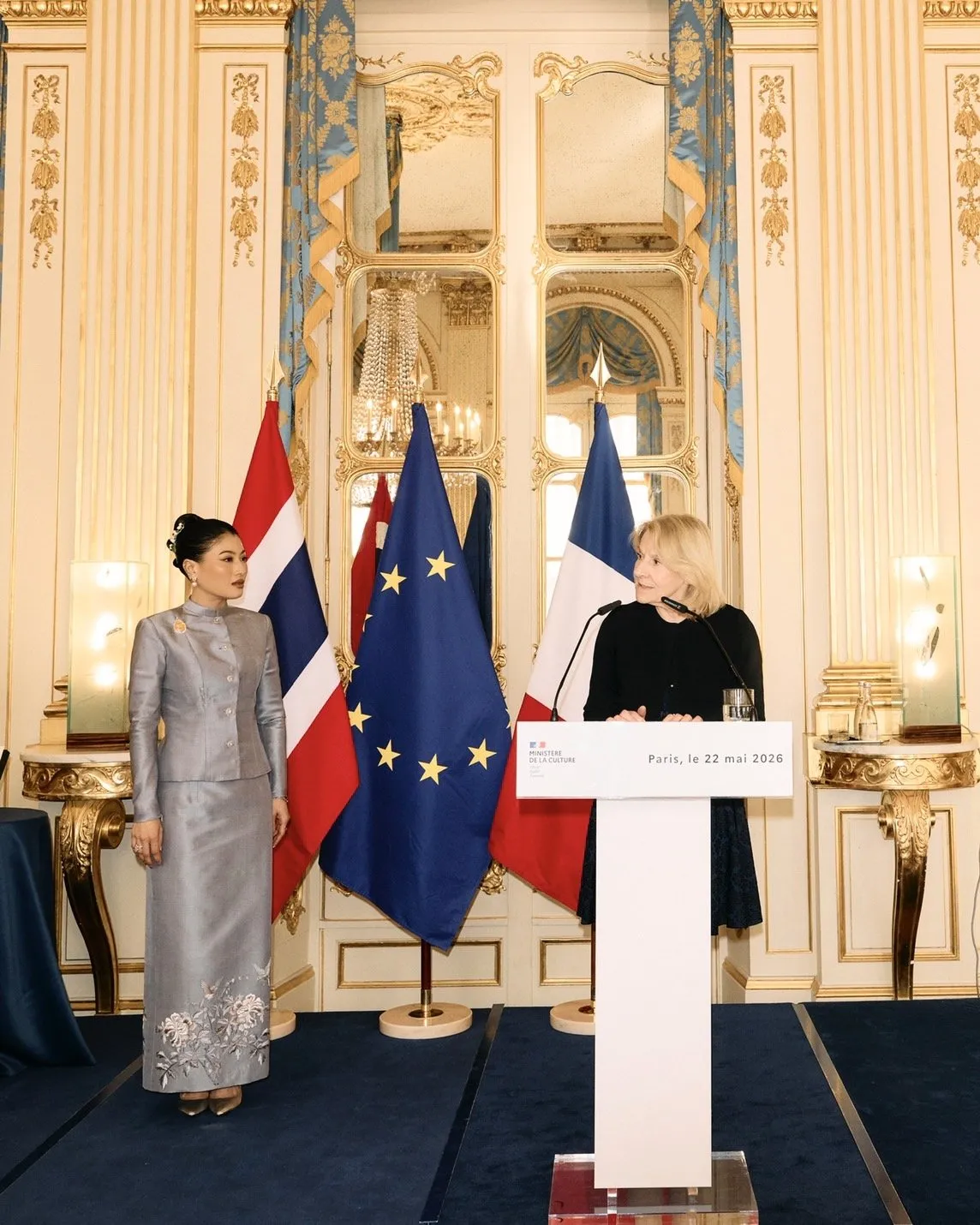 A wider shot showing the princess and French official flanking a white podium, backed by the Thai, European Union, and French national flags.