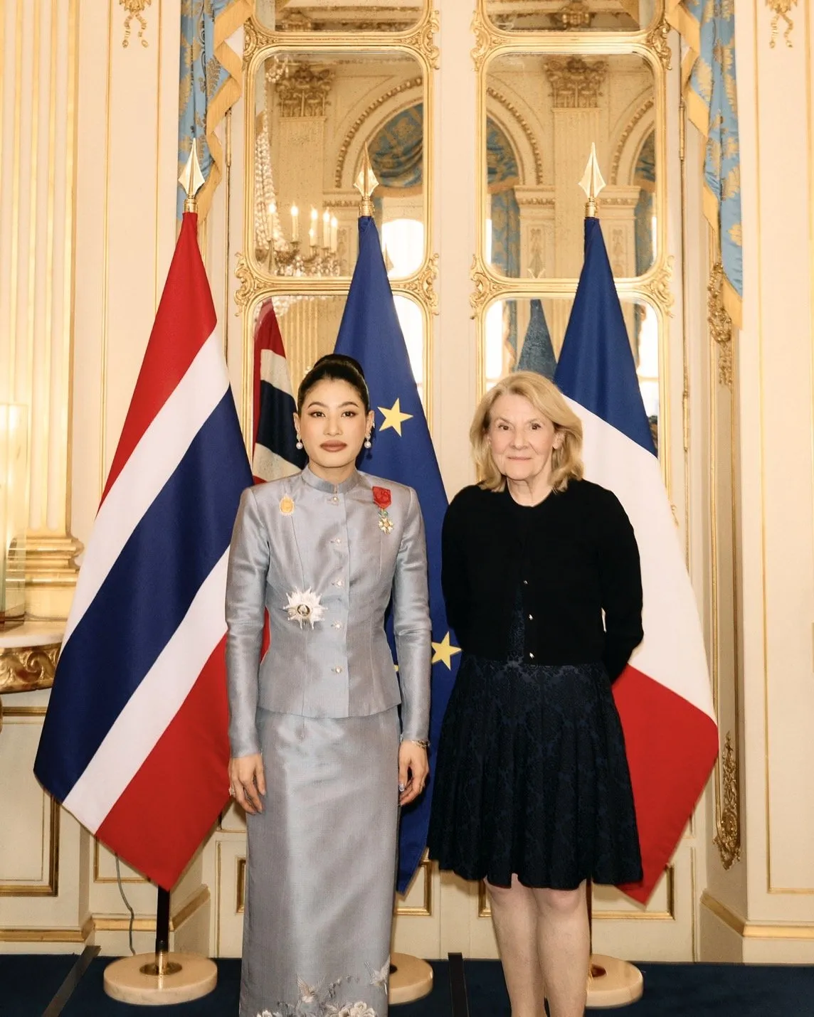 The Thai princess and the French official smile and pose together closely, proudly displaying the framed French Legion of Honor certificate.