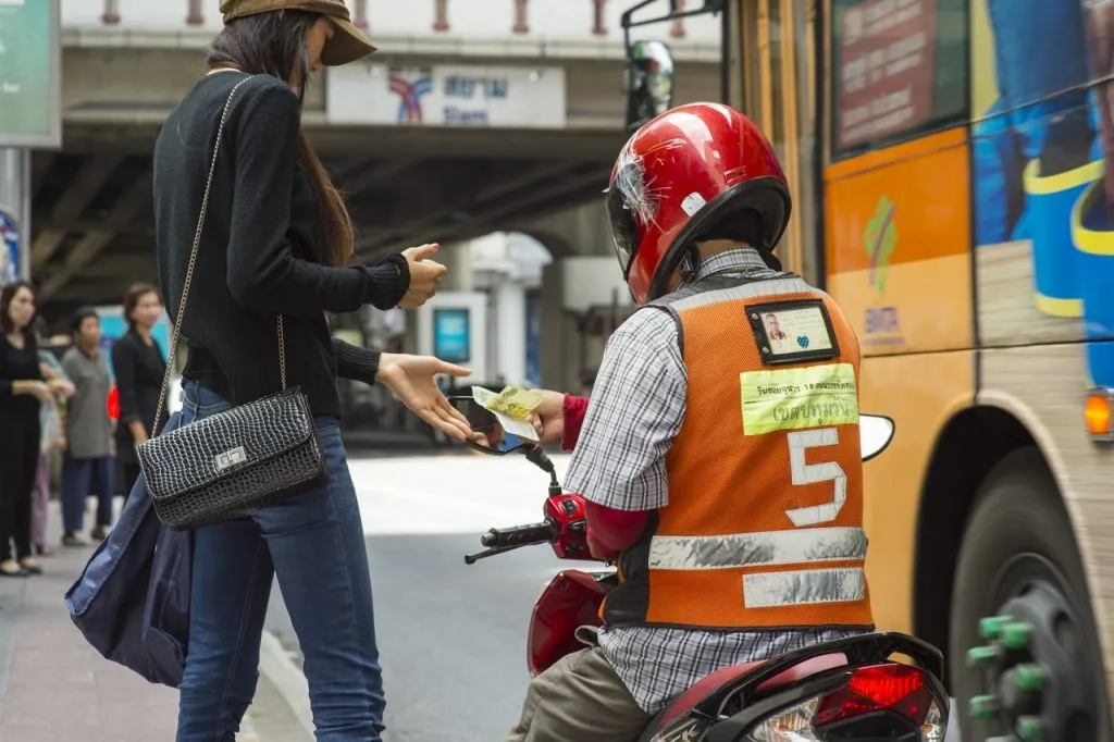 A woman paying for motorcycle taxi fee