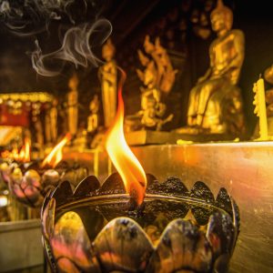 Oil lamps arranged in front of the Buddha statue in a Thai temple