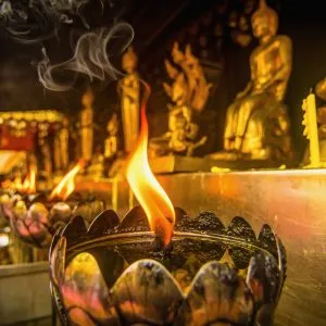Oil lamps arranged in front of the Buddha statue in a Thai temple