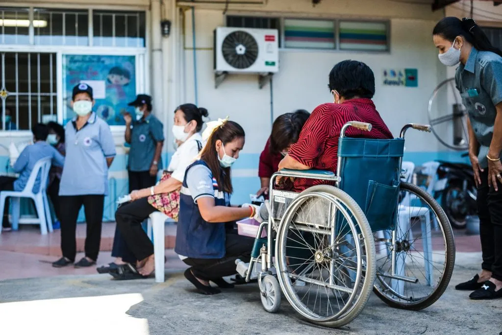 A nurse helping and assisting a patient in a wheelchair