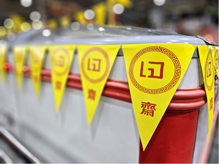 a foodstall lined with a string of triangle flag banners that say je in thai