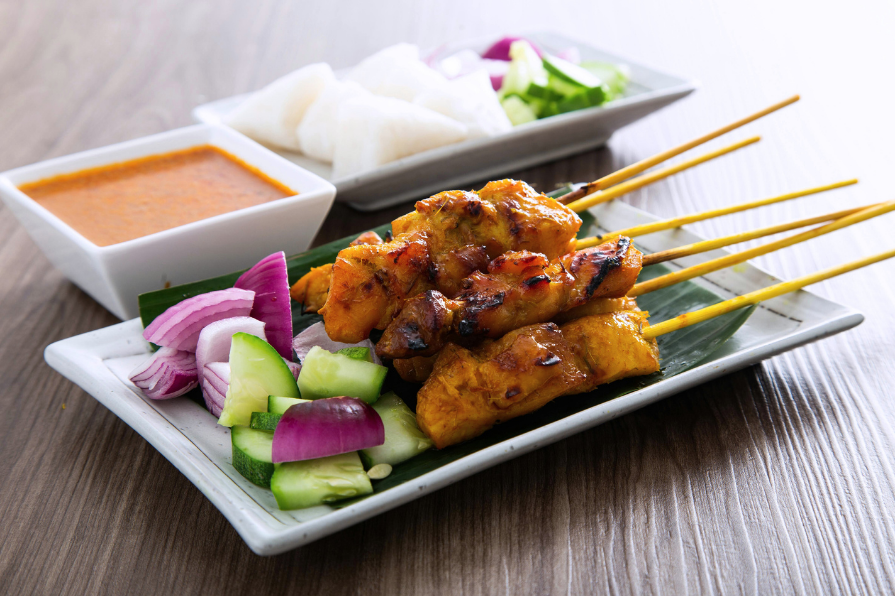 satay skewers served with satay or peanut sauce and garnished with pickled cucumbers