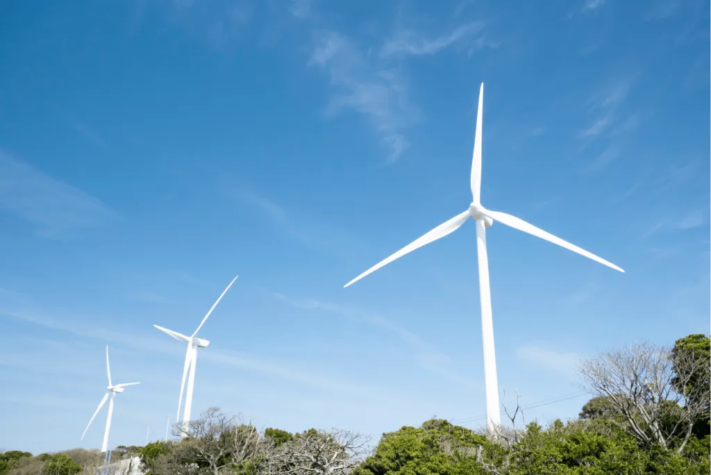 a series of wind turbines extending over treetops