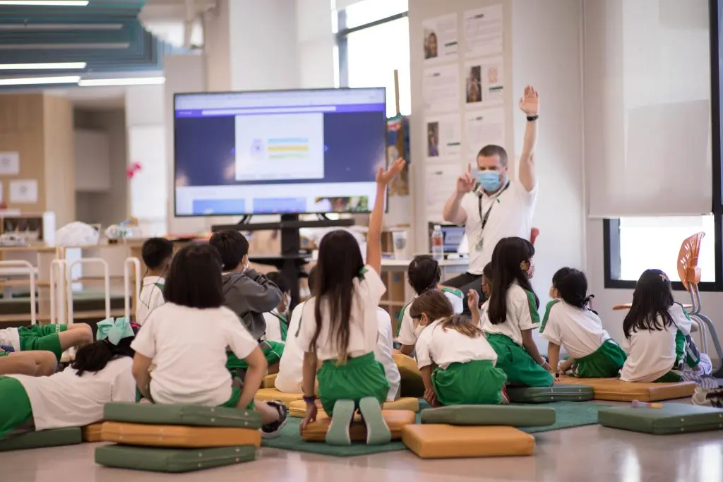 A teacher and primary students in a classroom at an international school in Thailand.