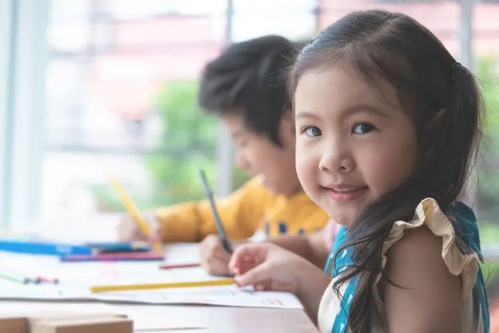 A young girl studying and smiling at the camera.