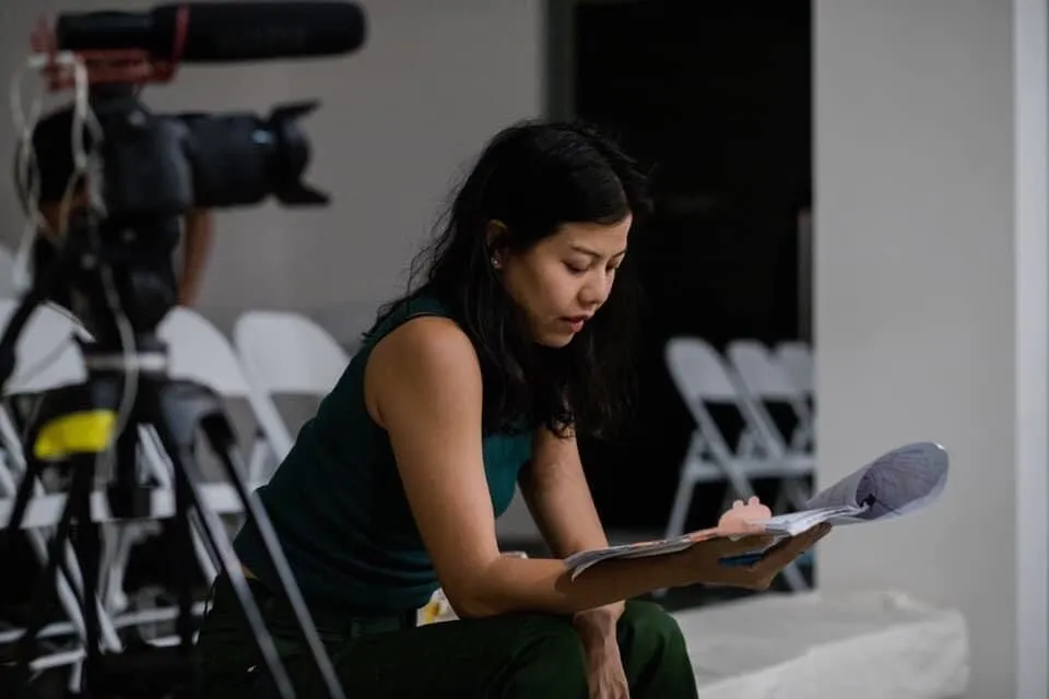 Bua thumbing through a well worn script for My Mother's Kitchen before the final performance at MAIIAM Contemporary Art Museum.