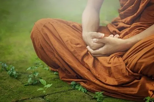 A monk sitting with his hands in his lap.