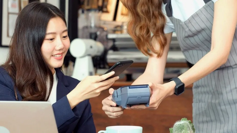 A woman using her phone to make a payment.