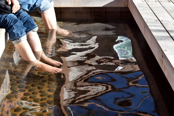 Two people dipping their feet into the hot spring.