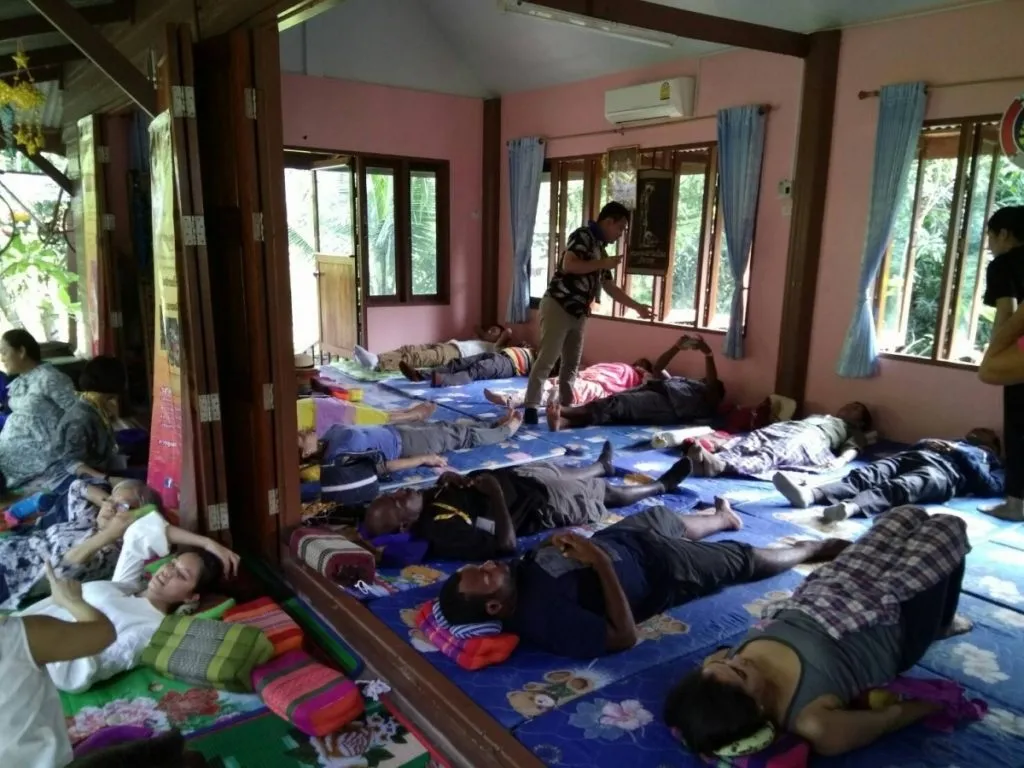 People lying down in rows waiting for their herbal compress massages.