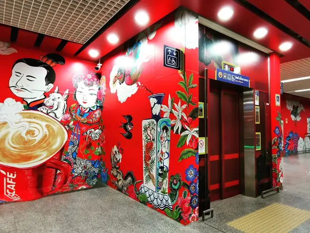Chinese-inspired artistic design and caricatures on red backdrop at Wat Mangkon Station.
