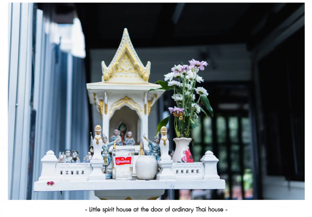 A small spirit house at the door of a traditional Thai home.