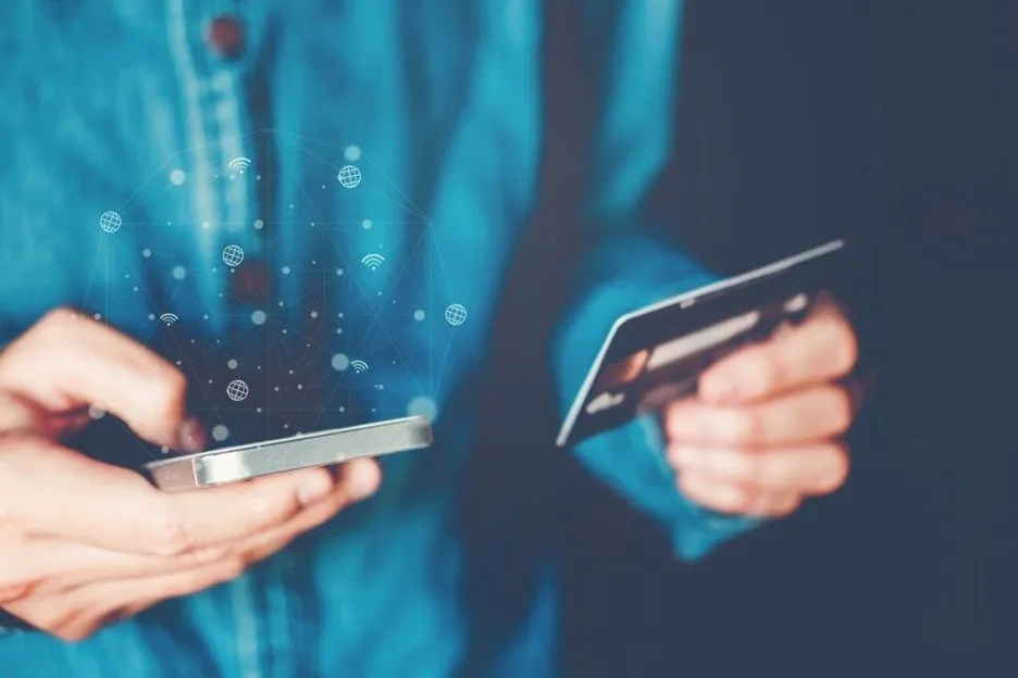A person holding a phone and a credit card.