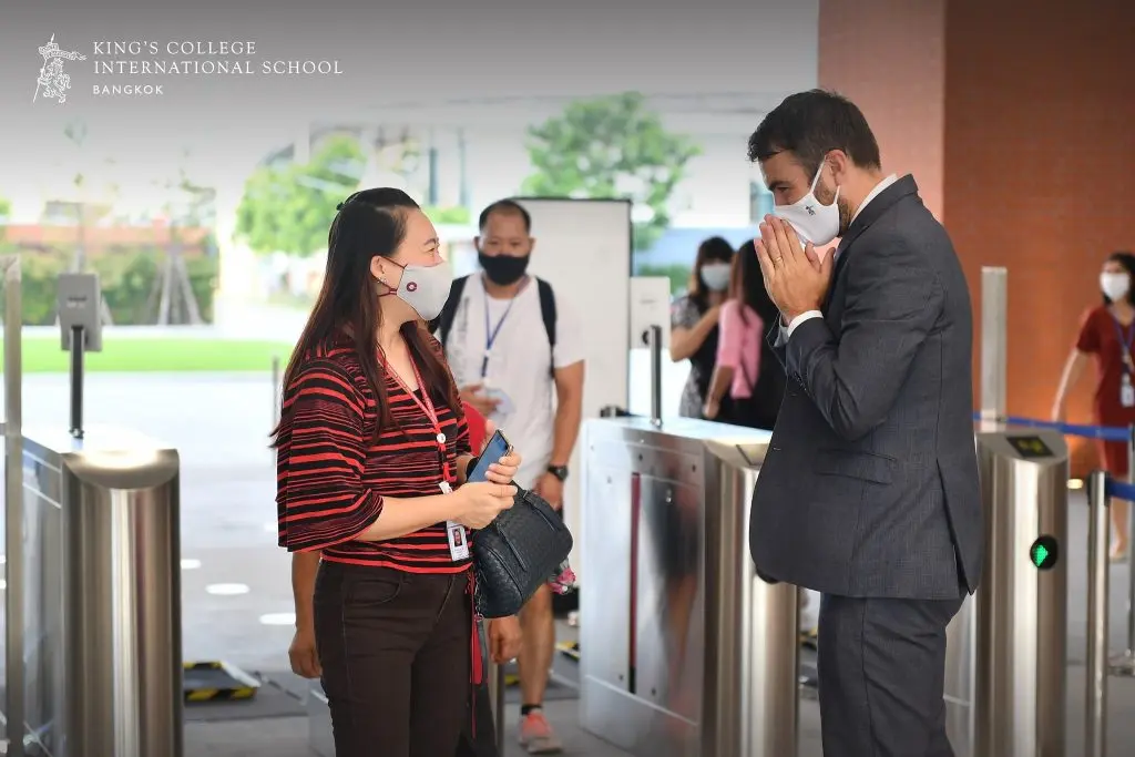 A man and women greet each other at the entrance to King's College International School, Bangkok.