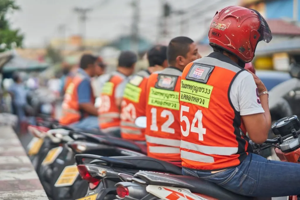 A series of motorcycle taxi drivers wearing their signature taxi vests.