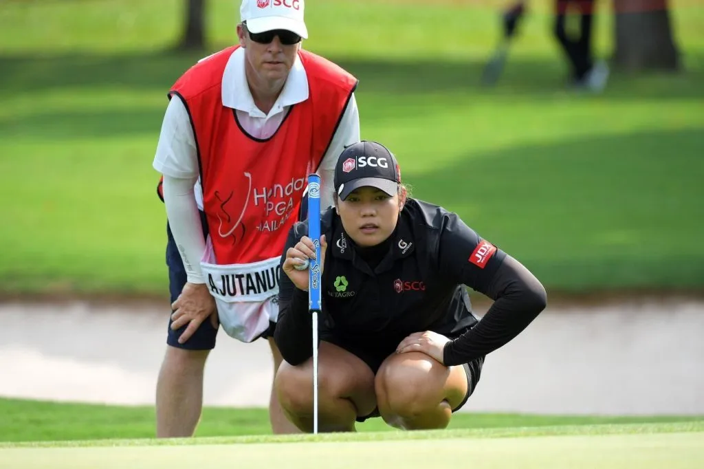 Ariya crouching down for a better view of her golf ball.