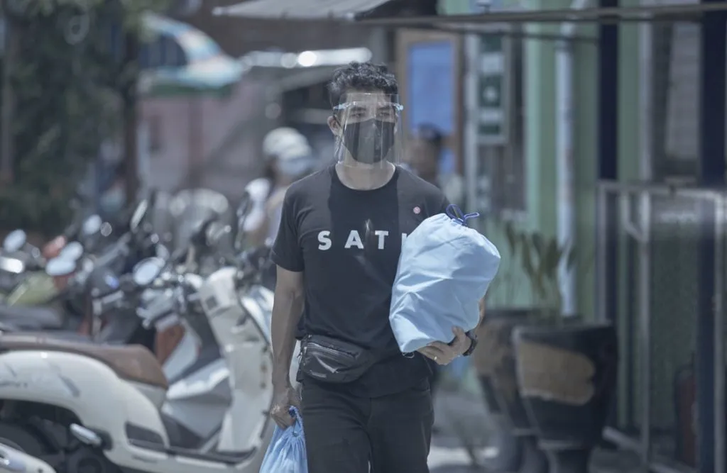 Sakson wearing a face mask and face shield while delivering essential supplies.