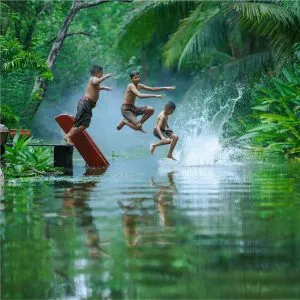 Two children playing and shaplising water in the river to combat summer heat.