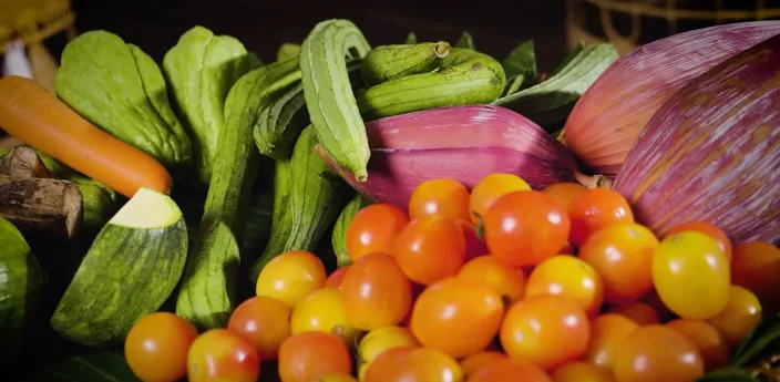 A picture of vegetables such as tomatoes, carrots, banana flowers and zucchinis. 