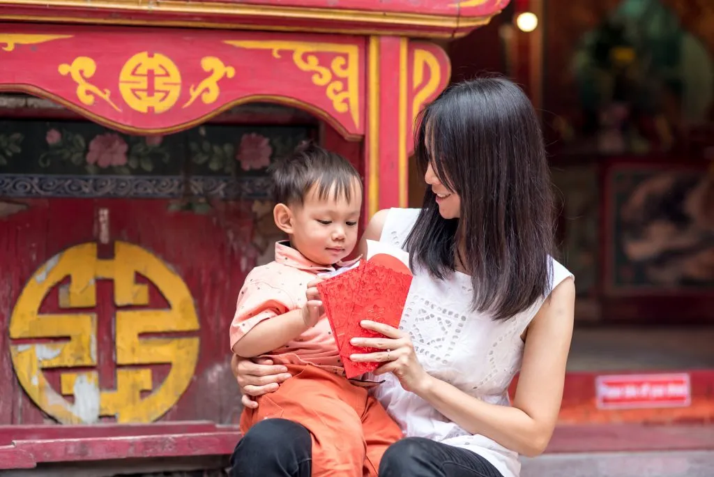 A mother giving her son red envelopes of money
