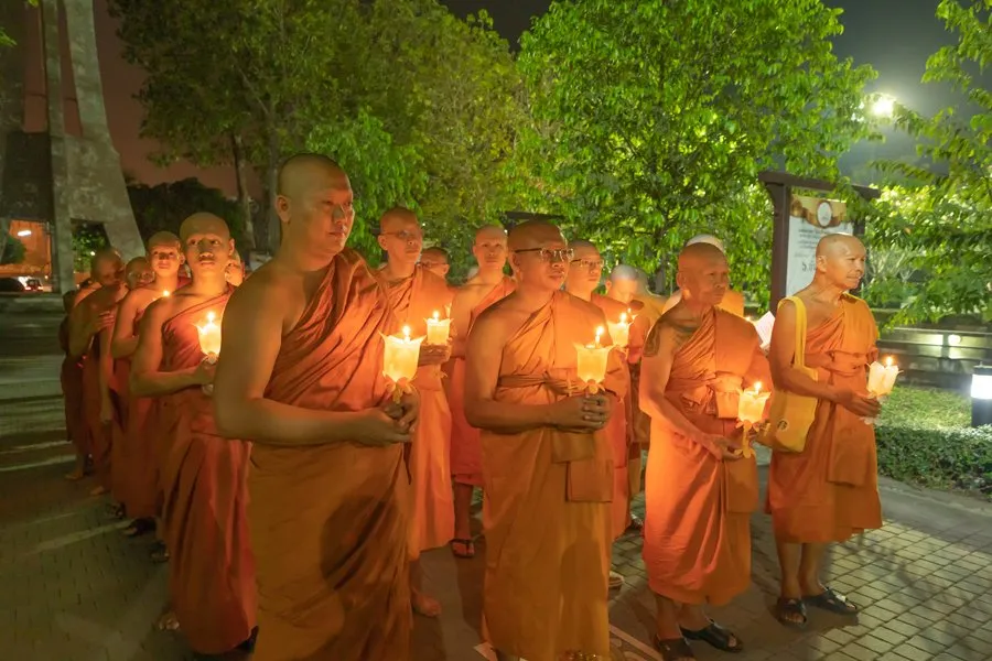 Thai monks standing and holding lighted candles in a Buddhist ceremony on Makha Bucha Day