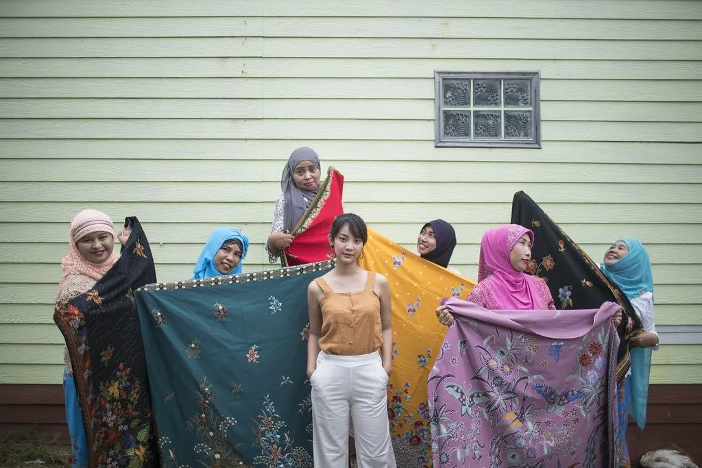 A visitor posing with Bang Khon Tee villagers and their colorful batik fabric
