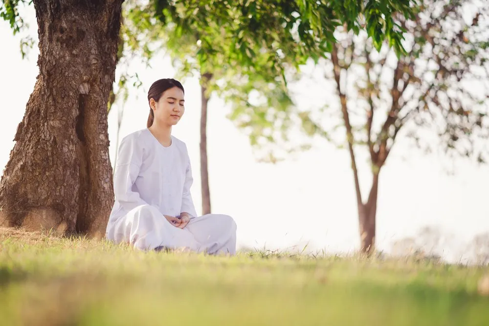 Thai woman meditating beneath a tree.