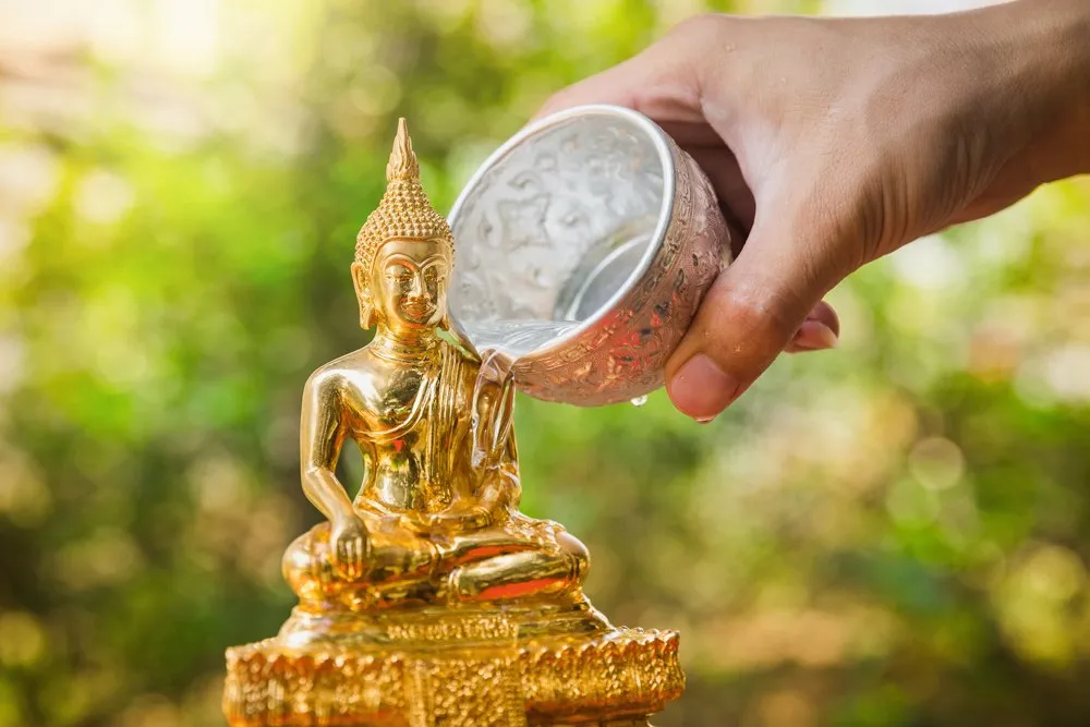 Bathing Buddha statue with scented water during Songkran Festival