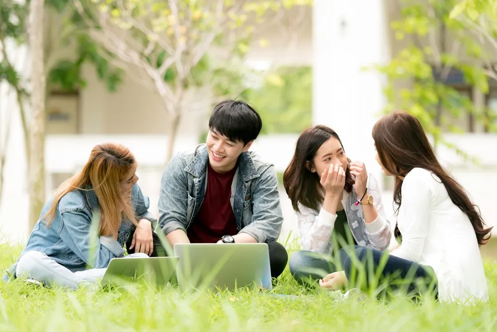 A group of university students sitting in a park and working on a project