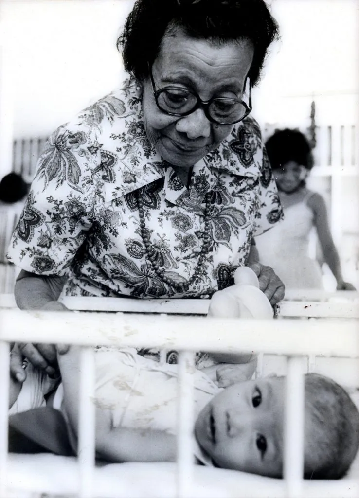 Dr Pierra checking on a baby in a baby crate at her orphanage