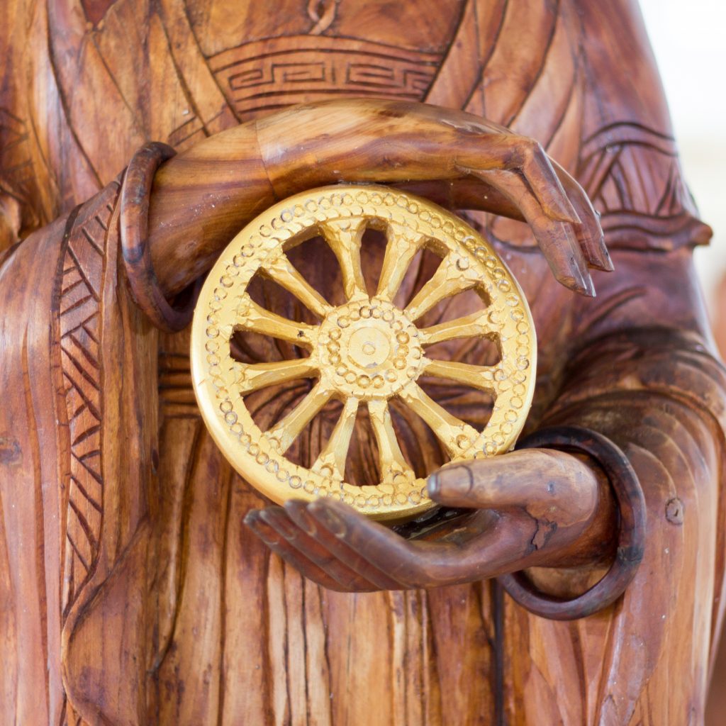 Carved wooden Buddha hands holding The Wheel of Dhamma