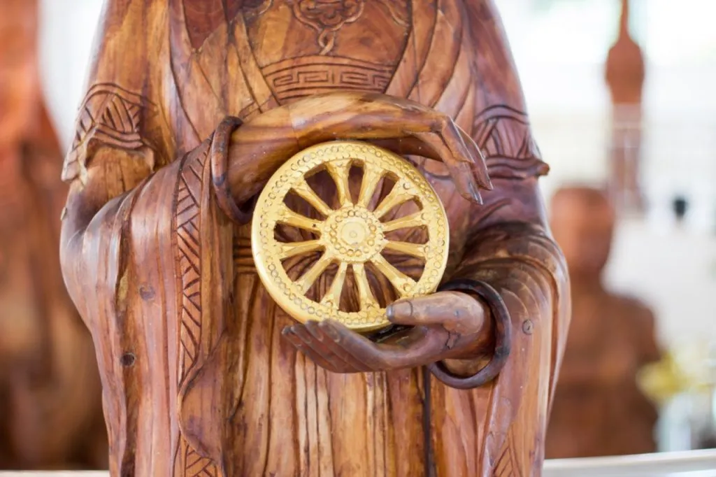 Carved wooden Buddha hands holding The Wheel of Dhamma