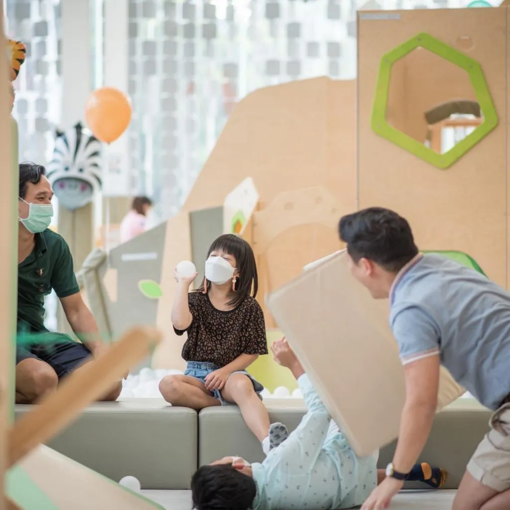Kids playing in a ball pit with two adults at Playville