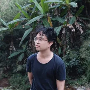 A picture of Komtouch Napattaloong looking away from the camera. Komtouch is a Bangkok-based filmmaker with an interest in themes of statelessness.