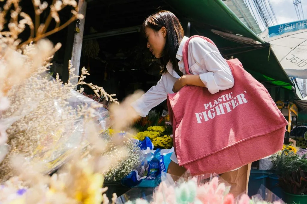 A girl holding a pink Plastic Fighter tote bag by Dao Ethical Gifts