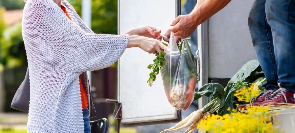 A grocery vendor handing over the groceries to the buyer