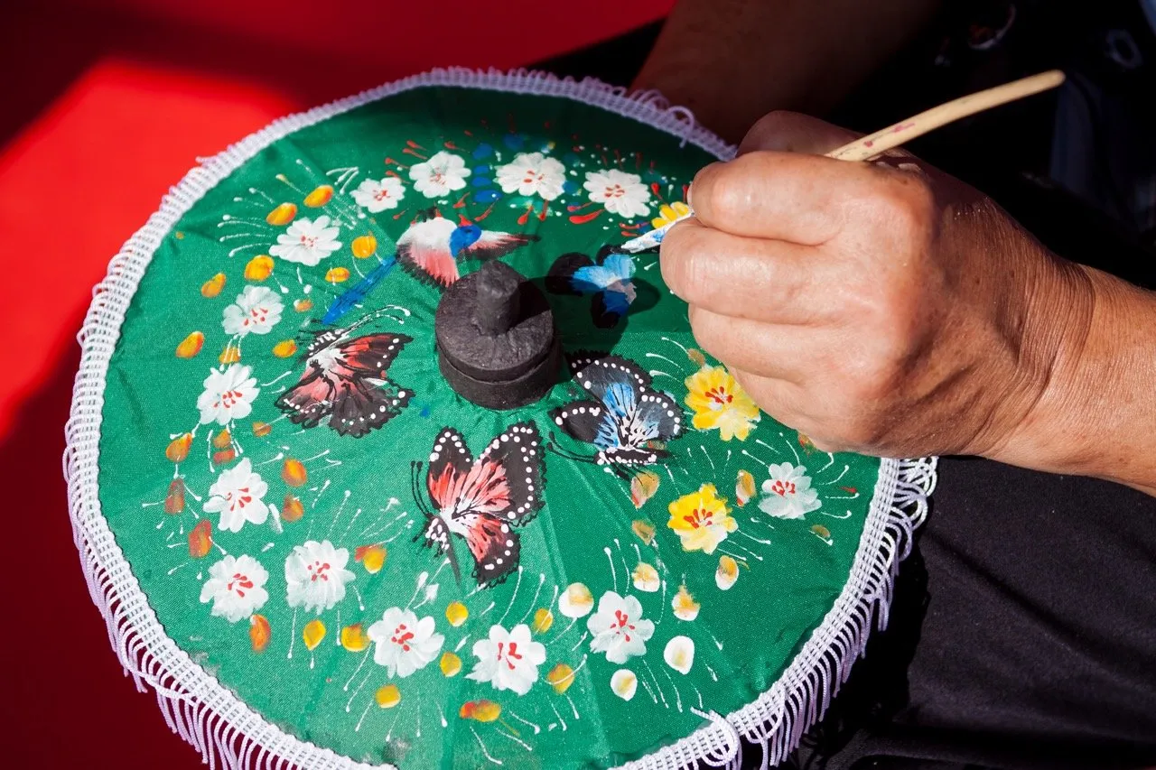A Thai artisan hand-painting a paper umbrella for the Bo Sang Umbrella Festival