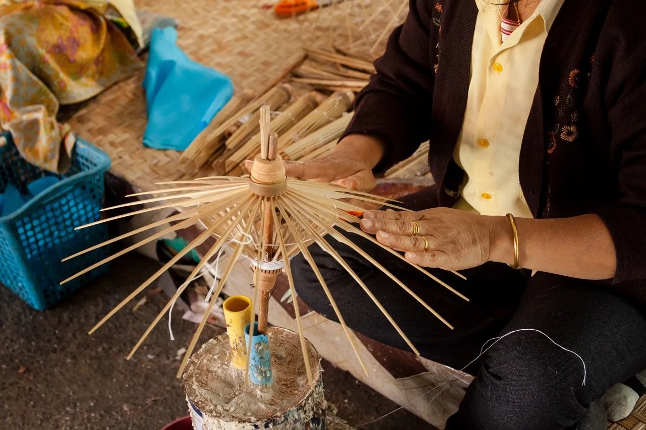 A person making an umbrella made of paper and fabric at the Bo Sang, Chiang Mai, Thailand