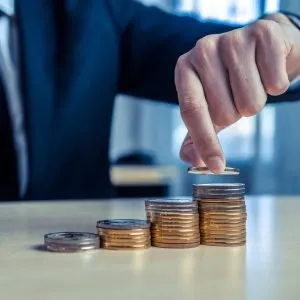 A business man placing a coin on a tower of coins