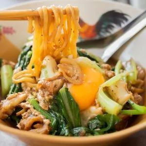 chopsticks holding Fried Hokkien Noodles, a traditional food of Phuket, Thailand