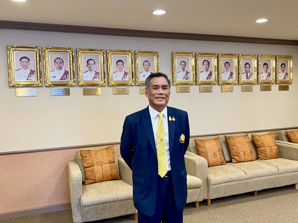 Ittiporn Boonpracong standing in front of portraits of former chairpersons of the Election Commission of Thailand