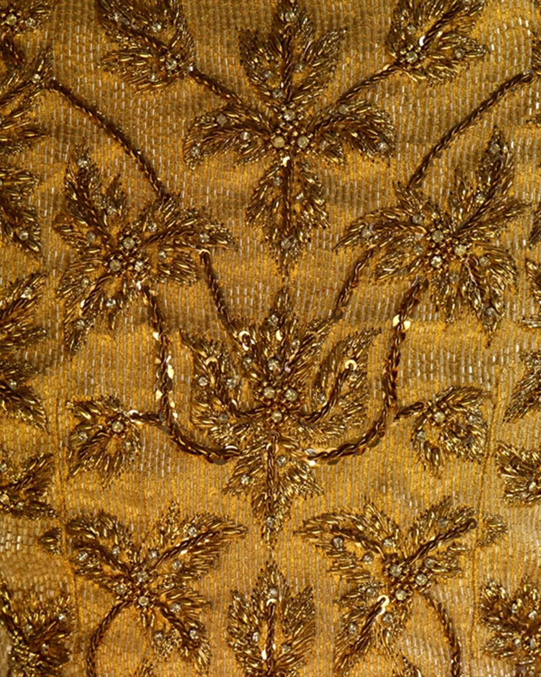 A closeup shot of the golden beads and jewelries intricately hand-sawn onto the fabric