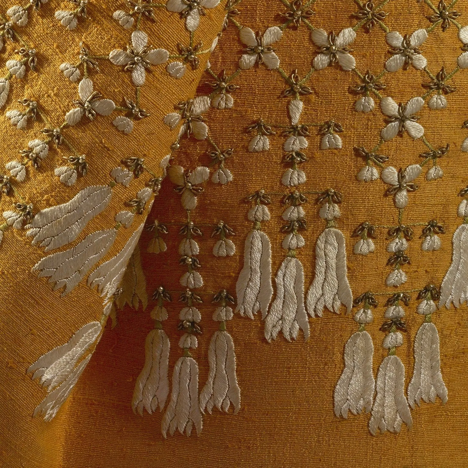 Close-up look at the intricate embroidery found towards the hem of the skirt includes motifs of jasmine flower garland commonly used in Thai ceremonies.