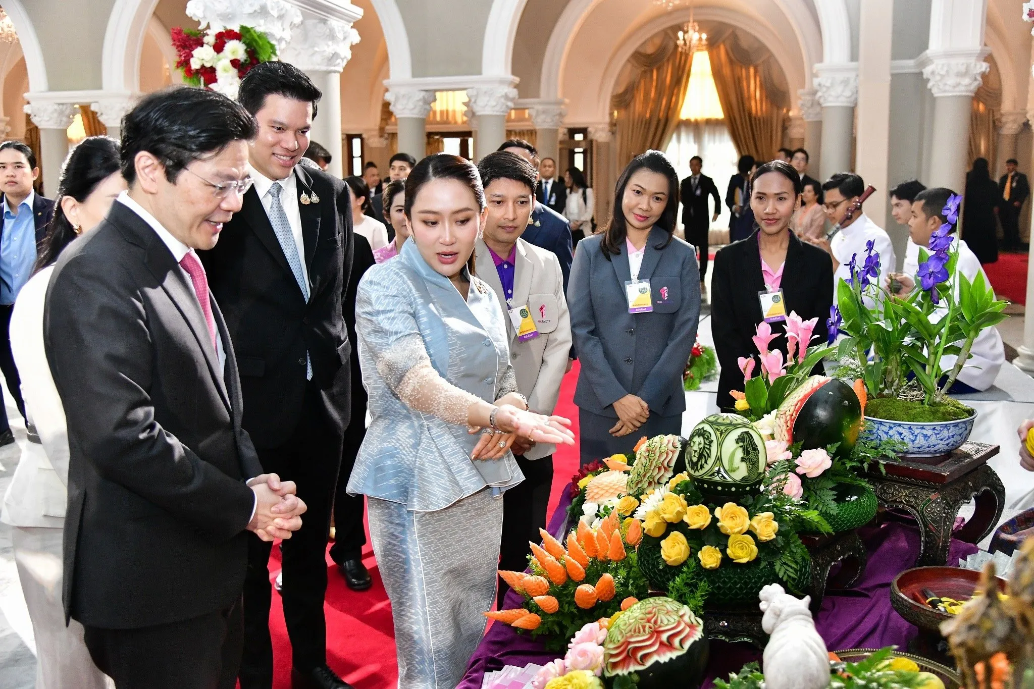 Prime Minister Lawrence Wong (left) and Prime Minister Paetongtarn Shinawatra (right) admiring traditional Thai fruit carving featuring Singaporean icons such as the Merlion