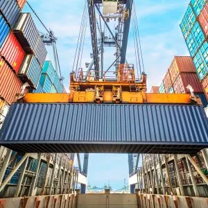 Containers being loaded onto a cargo freight ship using an industrial crane