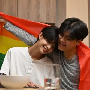 A same sex couple having a great time, with pride flag over their shoulders