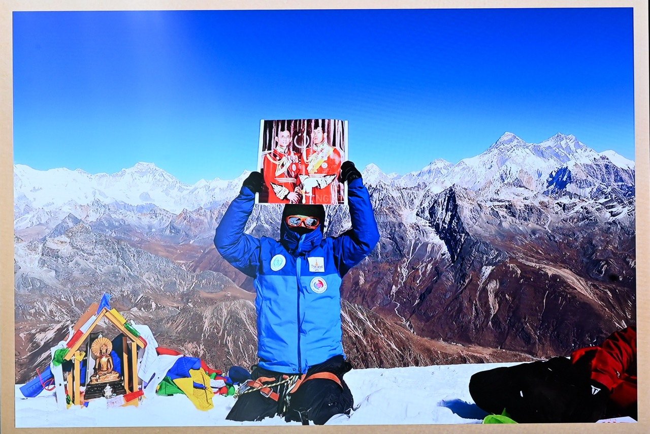 Vitidnan Rojanapanich on the summit of Mount Yasa Thak presenting an image of Their Majesties King Rama IX and King Rama X