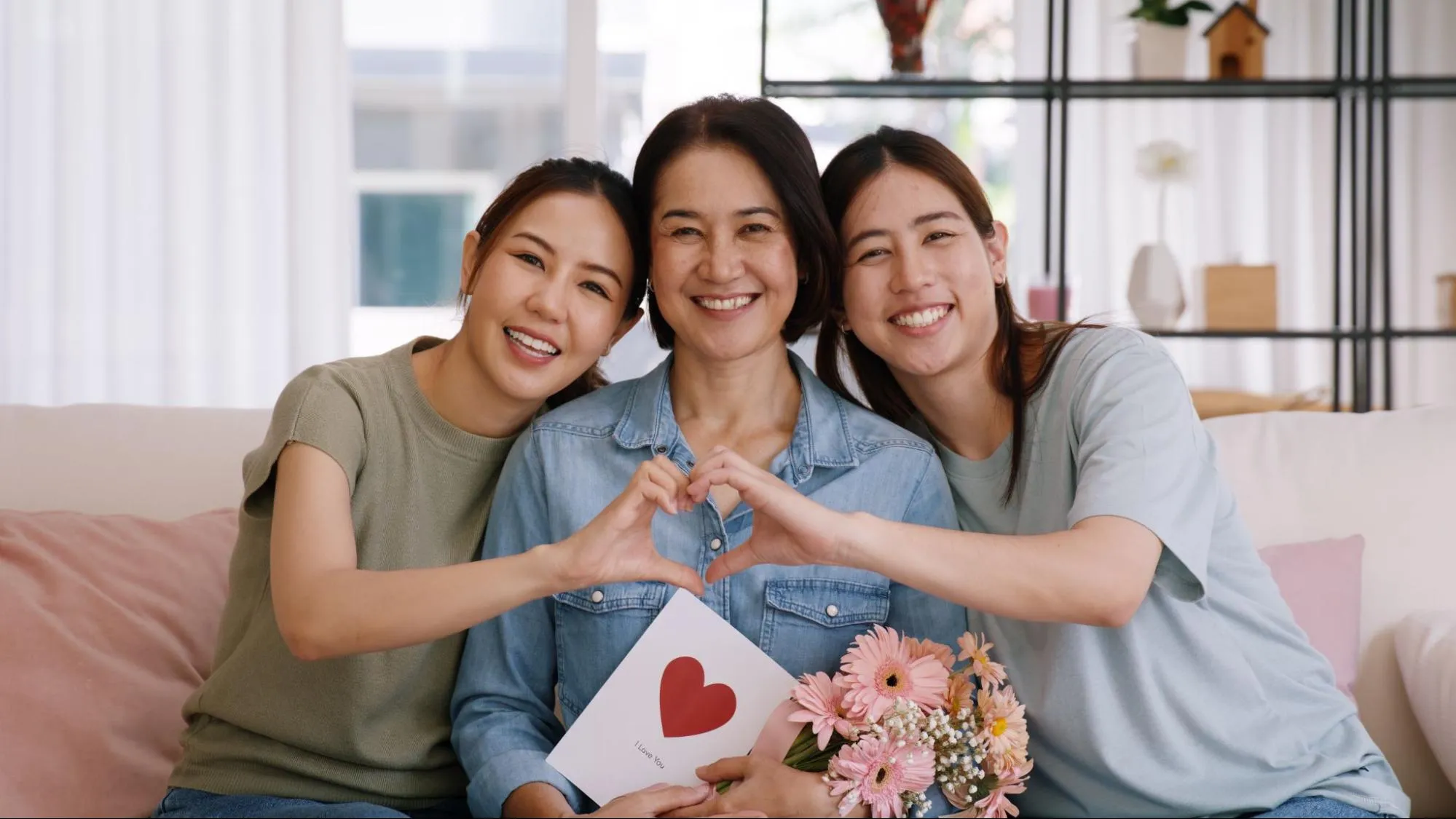 A family sitting on a couch, making a heart hand